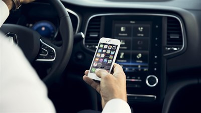 رجل يستخدم هاتفه في سيارة رينو